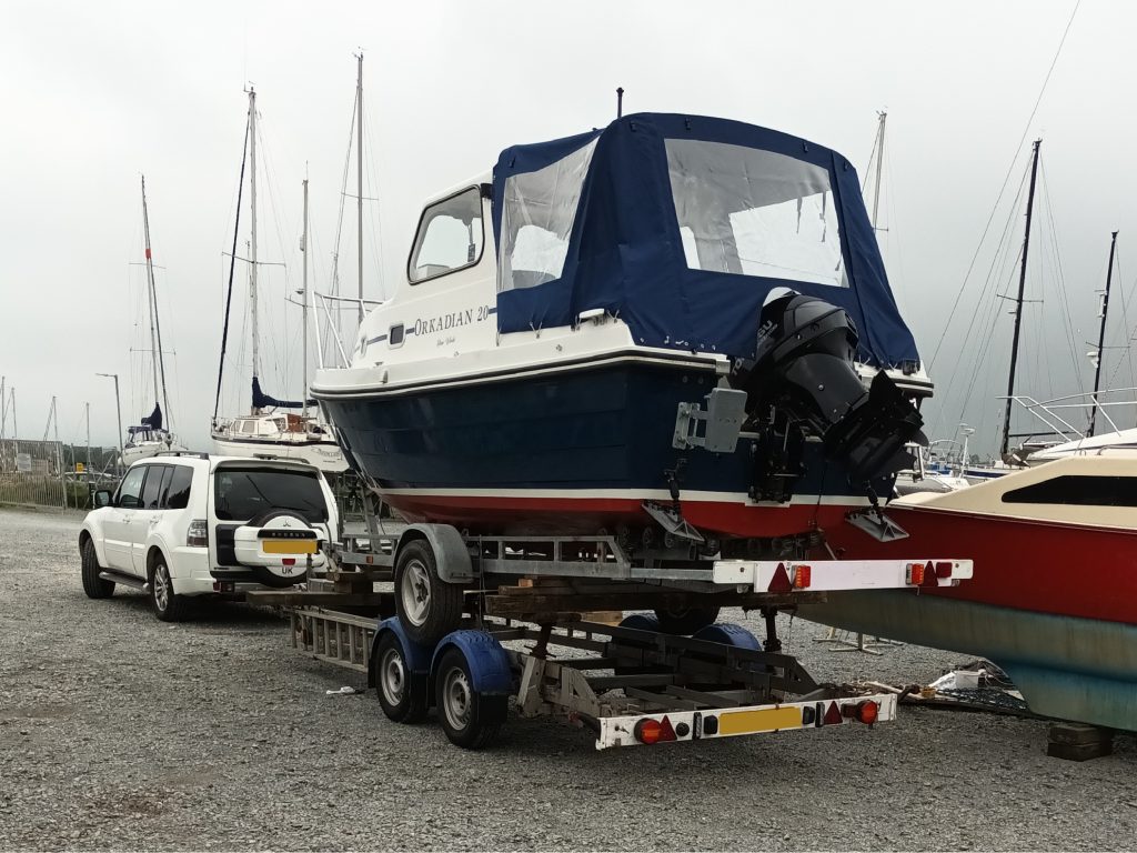 a powerboat on a trailer, on a trailer (piggyback to transport the trailer as well as the boat)