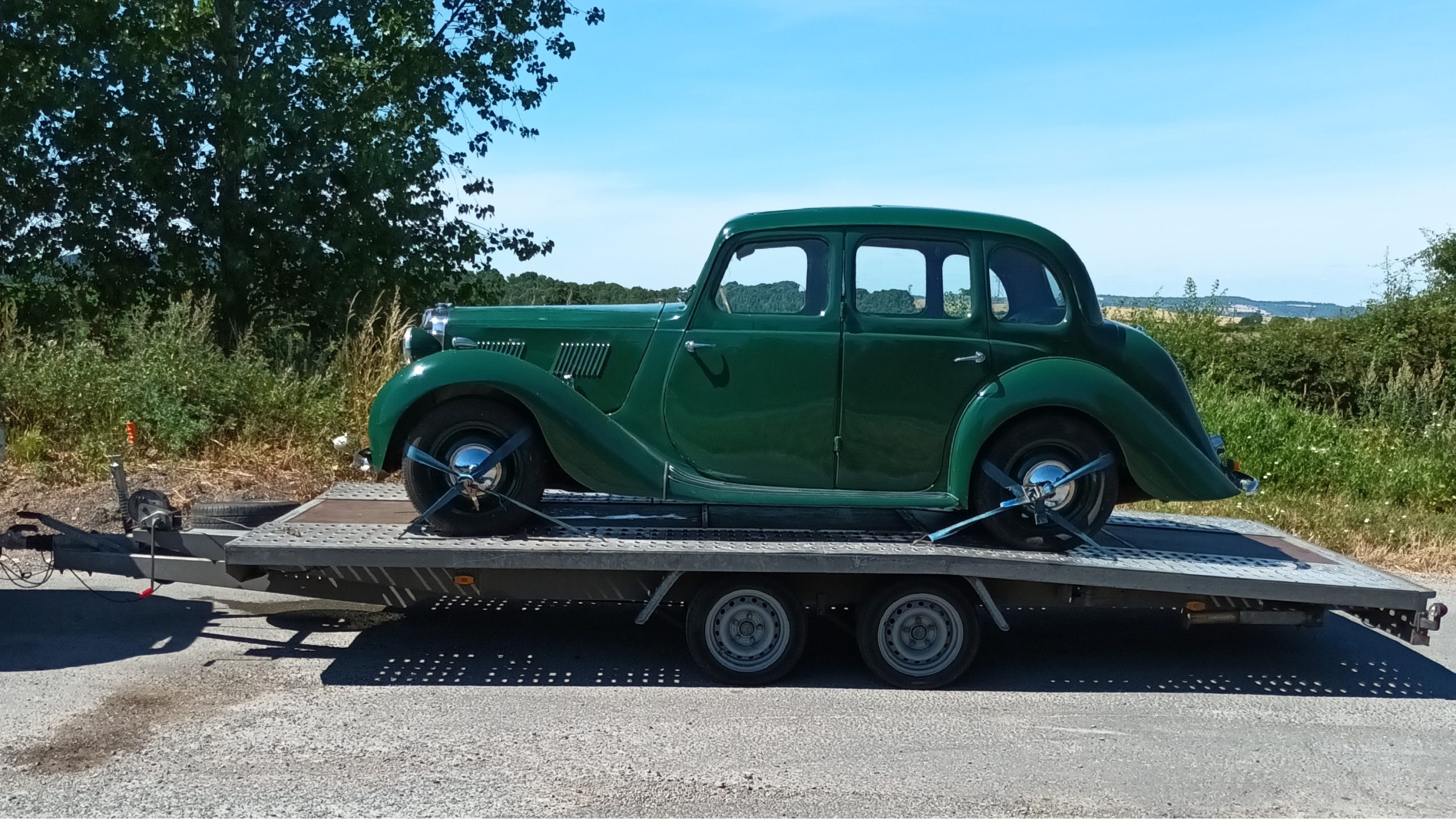 green vintage car loaded on a flatbed trailer